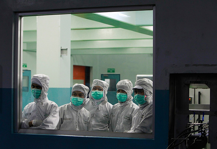 24 hours in pictures: Workers look through a window at the Kalbe Morinaga Indonesia milk factory