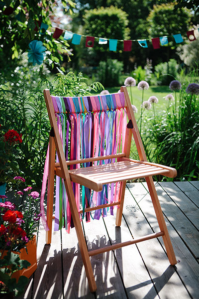 Brita - Garden decoration: Chair in sunny garden with colourful ribbons tied to the back