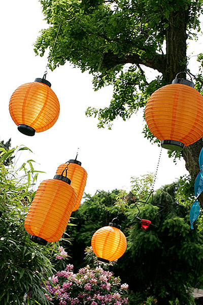 Brita - Garden decoration: Orange paper lanterns hanging from a tree outdoors