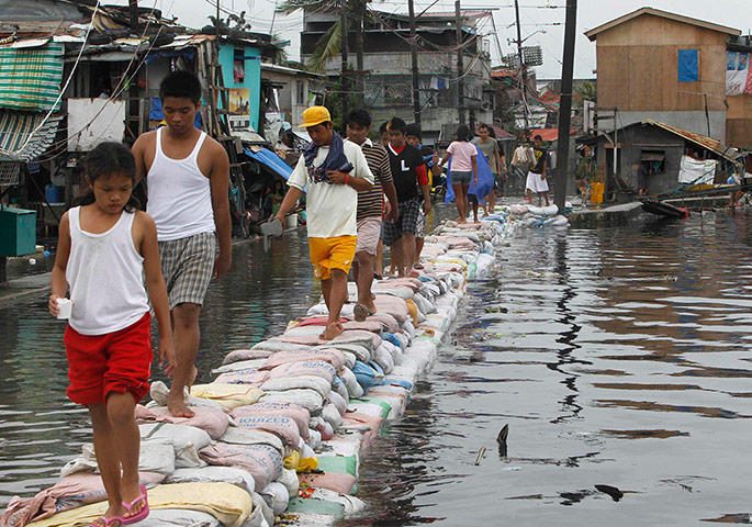 Manila flooding: Residents use sandbags to cross to the street