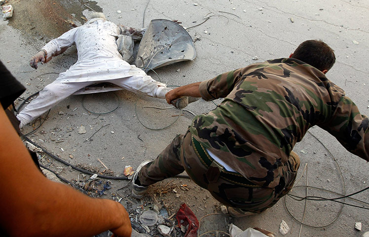 Syrian Conflict: A Free Syrian Army fighter drags a dead man 