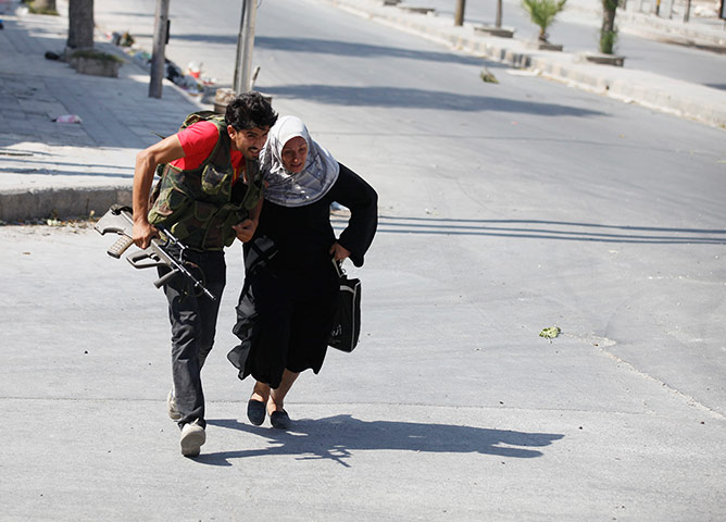 Syrian Conflict: A Free Syrian Army fighter helps a woman 