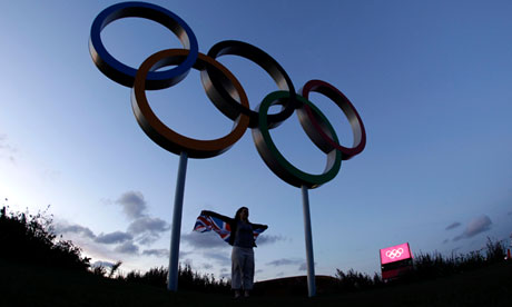 A visitor to Olympic Park poses with a set of Olympic Rings