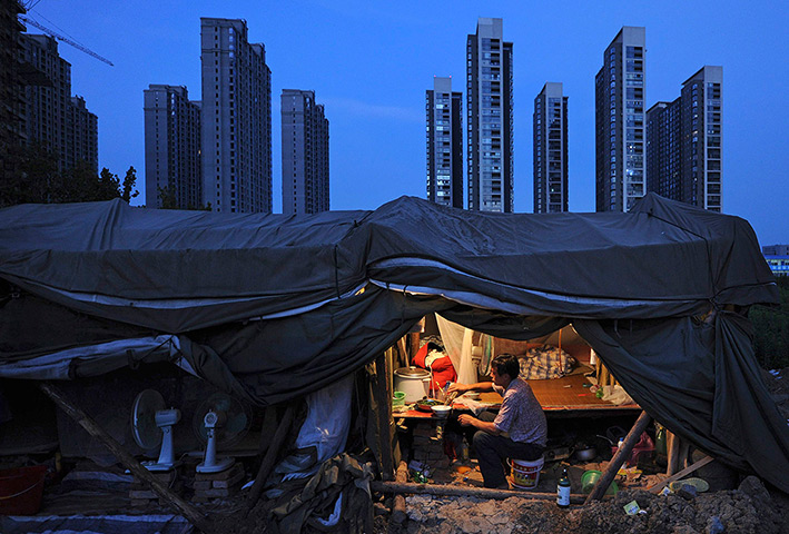 24 hours: Hefei, China: A labourer has his dinner in his shed