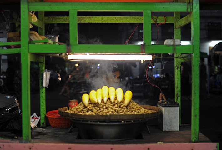 24 hours in pictures: Corn vendor waiting for customers in a street