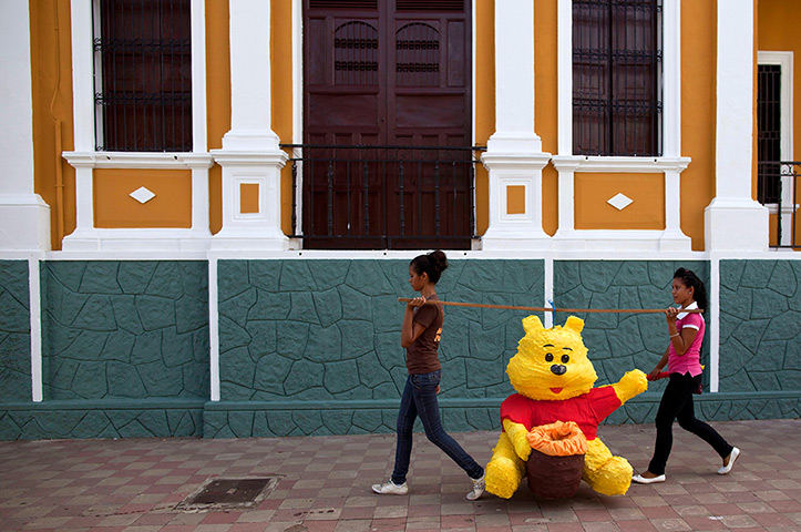 24 hours in pictures: Two girls carrying a pinata of Winnie the Pooh