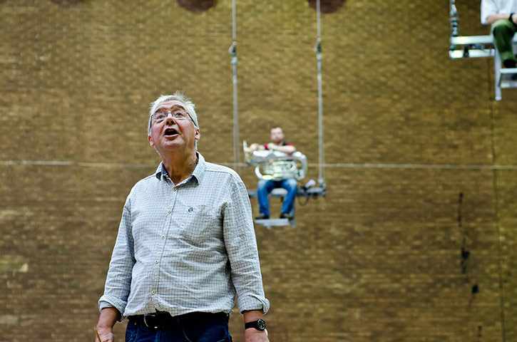 Mittwoch aus Licht: A man looks up with a tuba player on a trapeze behind him