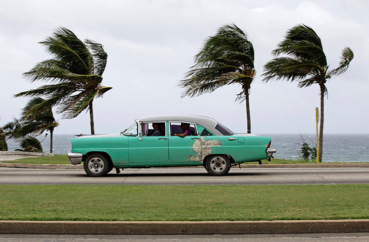 Tropical Storm Isaac: People ride a taxi as strong winds blow palm trees in Havana