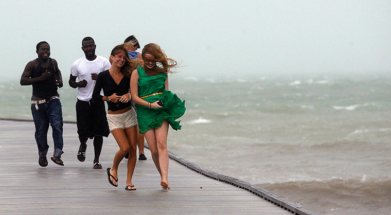 Tropical Storm Isaac: A group of people run back to shore along a pier