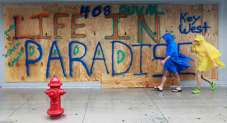 Tropical Storm Isaac: People walk past a boarded up shop front in downtown Key West 