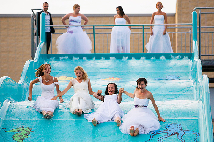 24 hours in pictures: Four newly married women in their wedding dresses use a water slide