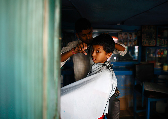 24 hours in pictures: A Nepalese boy gets his hair cut at the barber shop in Lalitpur