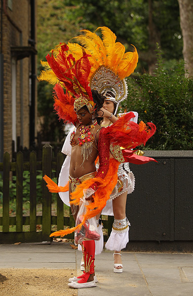 Notting Hill Carnival: A member of the Paraiso School of Samba helps adjust a performer's costume 