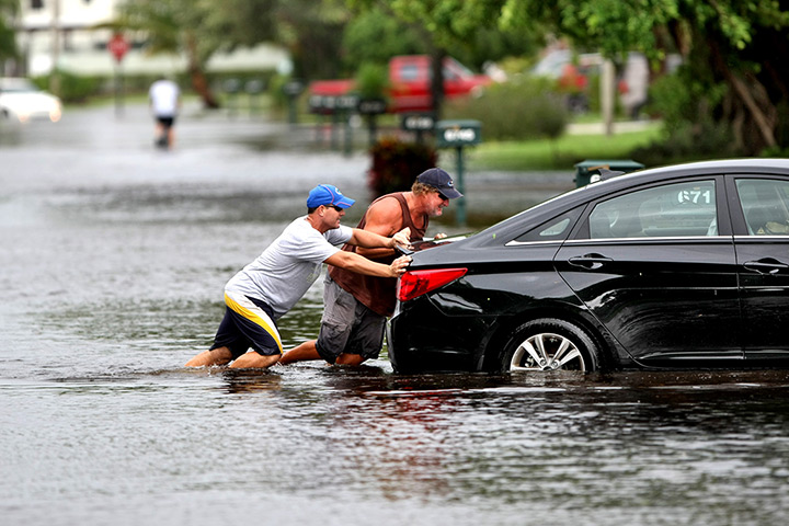Tropical storm Isaac: Residents help push a stranded car into a driveway along Alden Ridge Drive