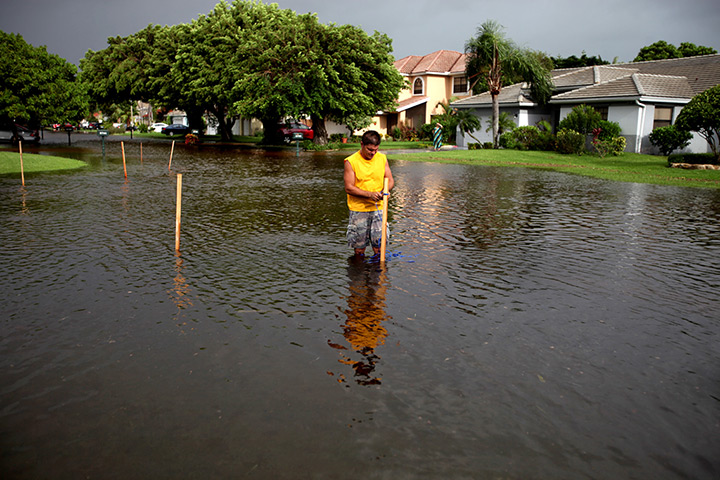 Tropical storm Isaac: Resident puts up wooden stakes up through flooded road in Boynton Beach