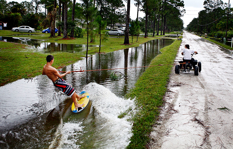 Tropical storm Isaac: Andrea Evans Pulls Shawn Chanutin on a skimboard along a flooded ditch