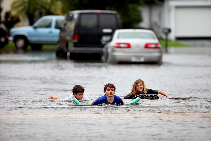Tropical storm Isaac: Children paddle down Holly Hill Drive using body boards in Boynton Beach