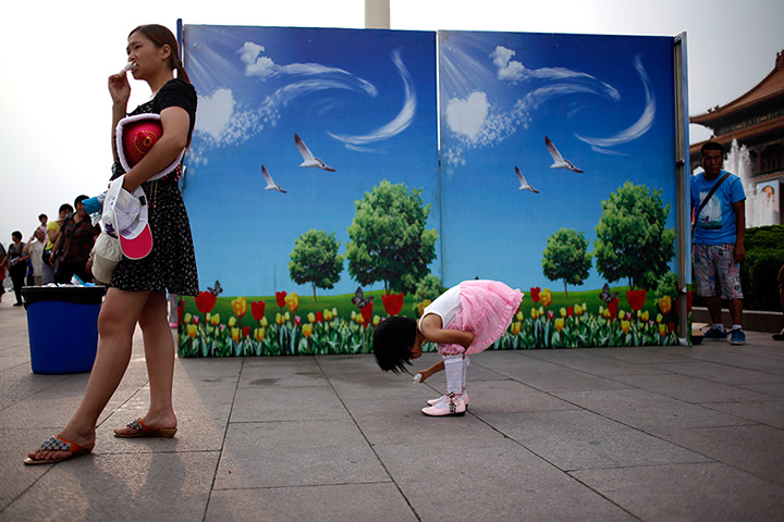 24 hours: Beijing, China: A child eats a popsicle near decorative hoarding