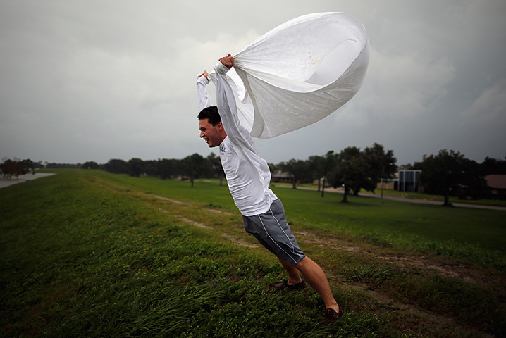 Tropical storm Isaac: Man holds a sheet open in the wind on the levee near Lake Pontchatrain