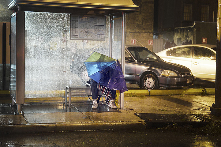 Tropical storm Isaac: A man shelters from the rain at a bus stop in New Orleans
