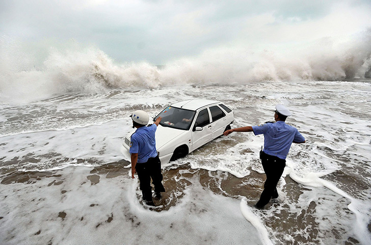 24 hours: Qingdao, China: Police officers gesture to a driver stranded by floods