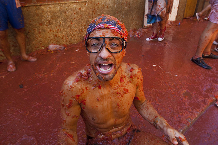 tomatina festival: People take pictures outside closed shops coverd in tomatoes