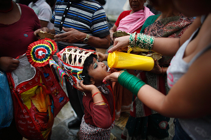 24 hours in pictures: A girl, dressed up as a holy cow, is offered milk during a parade