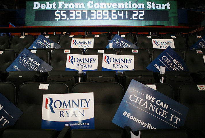 Republican convention: Campaign signs sit on seats in front of a US national debt clock acrued