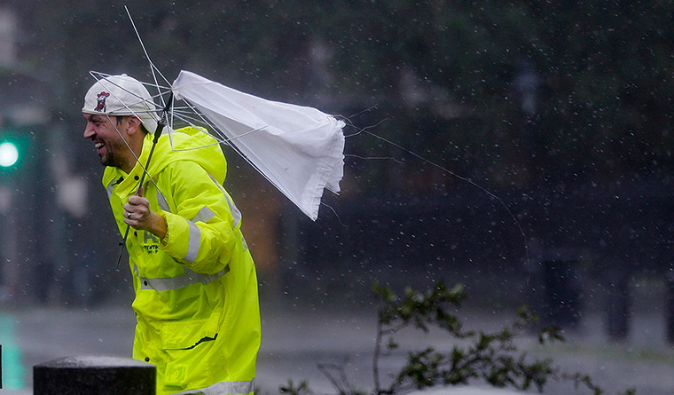Hurricane Isaac: A man holds a broken umbrella in the wind