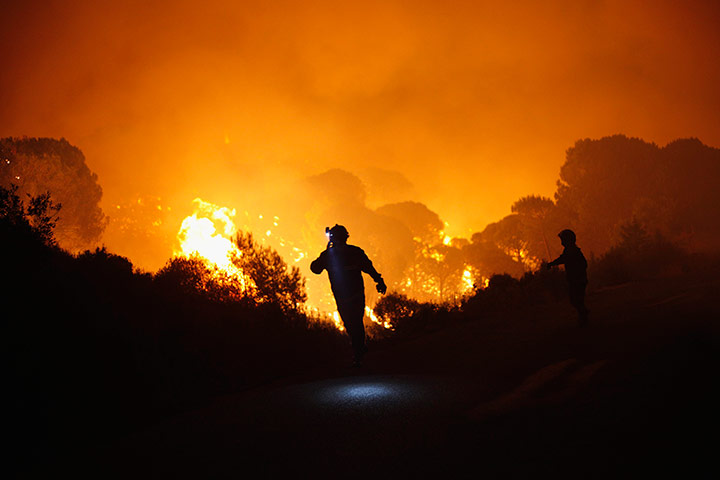 24 Hours: Coin, Spain: Firefighters walk past a blaze at a forest in Barranco Blanco