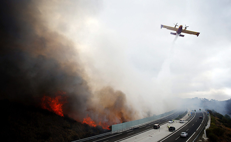 fires on costa del sol: A fire fighting aircraft sprays water over a forest fire in Calahonda 