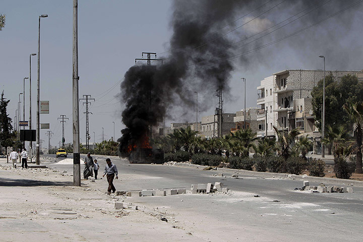 Aleppo: Syrians walk past a burning vehicle in t