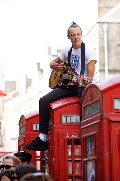 Royal Mile: A performer plays the guitar from on top of a phone box 