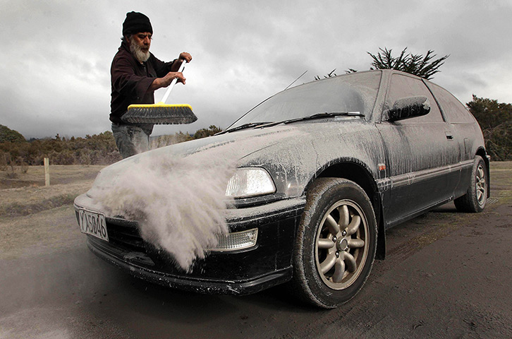 Mount Tongariro erupts: A man sweeps ash from a car in Rangipo