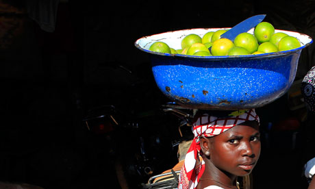 A woman balances a container of oranges for sale on her head in a village near Abuja