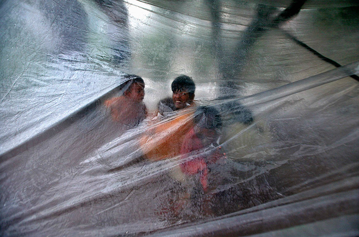 24 hours in pictures: Roadside dwellers protect themselves from rain with a plastic shee