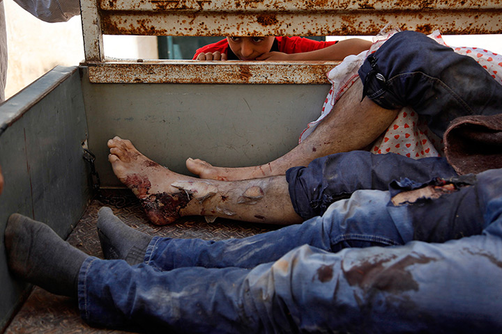 24 hours in pictures: A Syrian boy looks at the bodies of nine Syrians on a truck