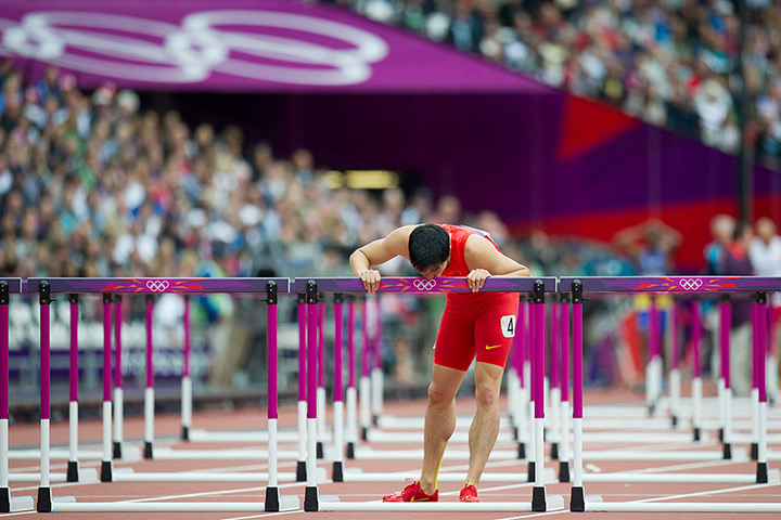 Winners and losers: Xiang Liu of China stops to kiss the last hurdle after he crashed out