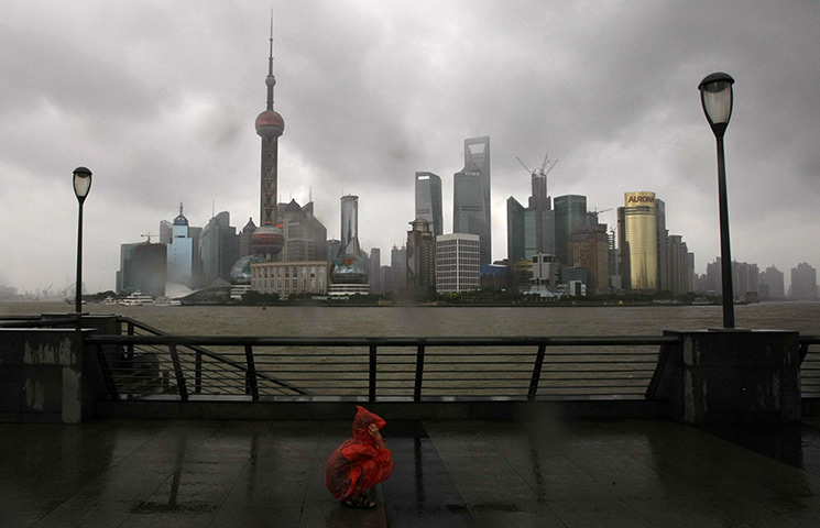 24 hours: Shanghai, China: A person squats at the Bund as Typhoon Haikui hits