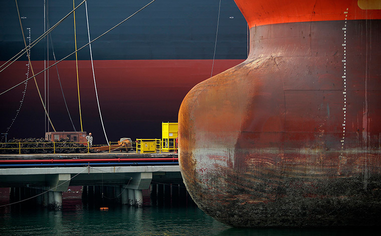 24 hours: Singapore: A worker is dwarfed by vessels berthed at a pier 