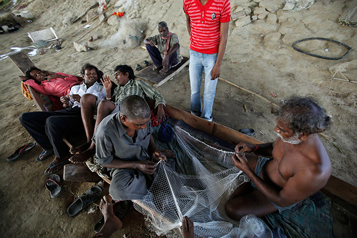24 hours: Lucknow, India: Indian fisherman rest in a boat as they fix their nets 