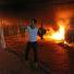 Benghazi protest: An armed man waves his rifle as buildings and cars are engulfed in flames