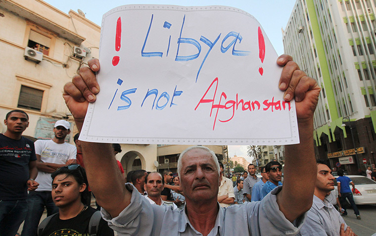 Libya protests: A demonstrator holds placard during a rally 