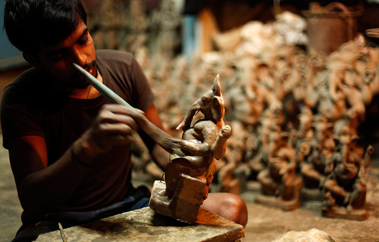 24 Hours: Allahabad, India: An artisan works on a mud idol