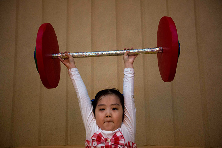 24 Hours: Pyongyang, North Korea: A school girl lifts a toy barbell