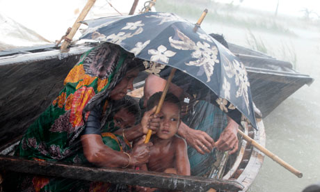 A woman sits with her child in a boat during heavy rains at a flooded village in Kurigram