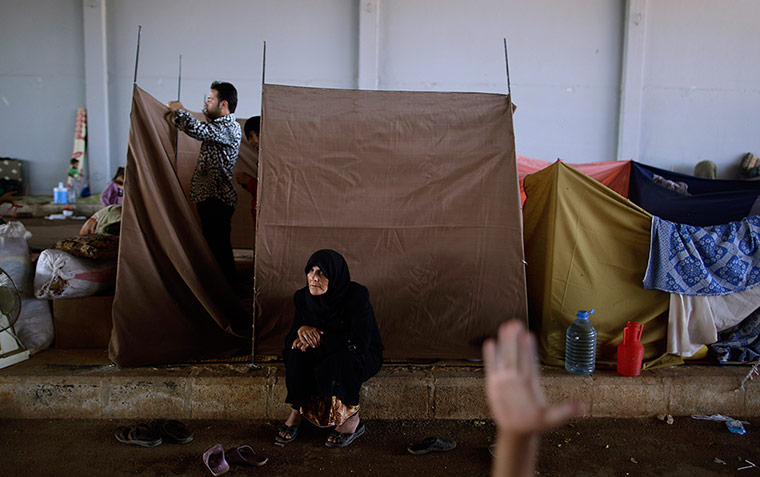 20 photos: A Syrian woman rests while her son constructs a makeshift tent