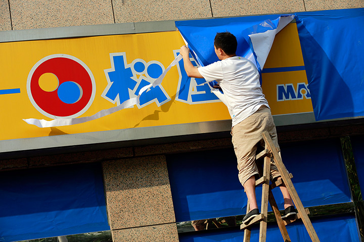 Anti-Japan protests: A worker covers a sign of a Japanese restaurant chain in Shanghai
