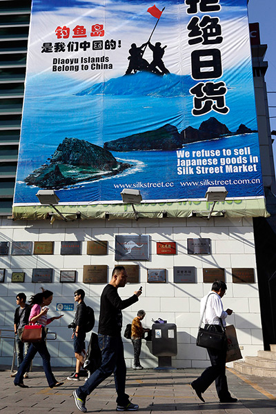 Anti-Japan protests: People walk past a giant poster declaring boycott of Japanese goods