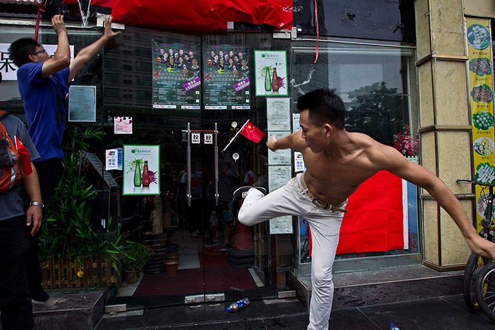 Anti-Japan protests: A man kicks the door of a Japanese pub in Shenzhen